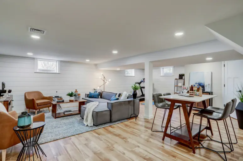 Bright open-plan home remodel with white kitchen, living area, and recessed ceiling lights.